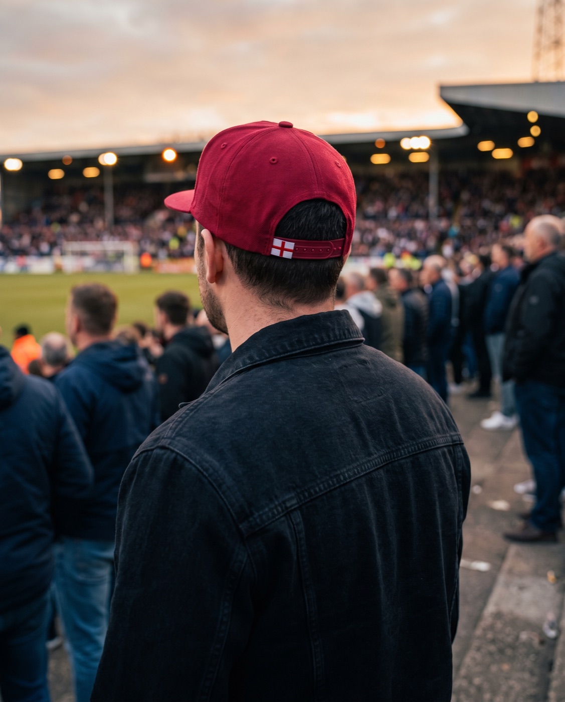 Supporter on a football terrace wearing a red MEGA cap